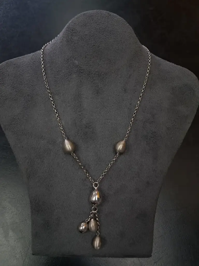 Silver Necklace With Multiple Teardrop-Shaped Beads And A Drop Pendant.